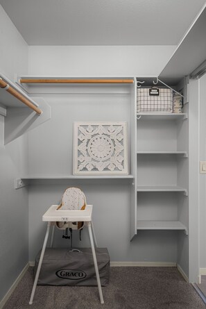 A child's high chair with a Graco brand bag, a white decorative wall piece, and a grey storage unit with shelves. - Spacious Retreat w/ Free Heated Pool – Close to Stadium & Ballparks! (Peoria)