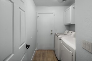 A laundry room with a washing machine, dryer, and a door. - Spacious Retreat w/ Free Heated Pool – Close to Stadium & Ballparks! (Peoria)