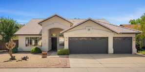 A single-story house with a garage, a front entrance, and a small garden area. - Spacious Retreat w/ Free Heated Pool – Close to Stadium & Ballparks! (Peoria)