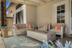 Un espace extérieur aménagé, abrité et doté d’un foyer, de fauteuils confortables et d’un sol en béton.