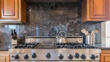 A kitchen with a stainless steel Viking stove, oven, and a marble backsplash.