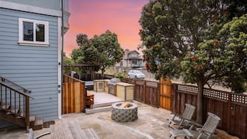 A backyard with a fire pit, outdoor seating, and a wooden deck.