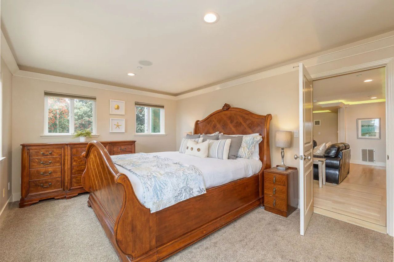 Un dormitorio con una cama de madera, una mesita de noche, un aparador y una puerta que da a otra habitación.