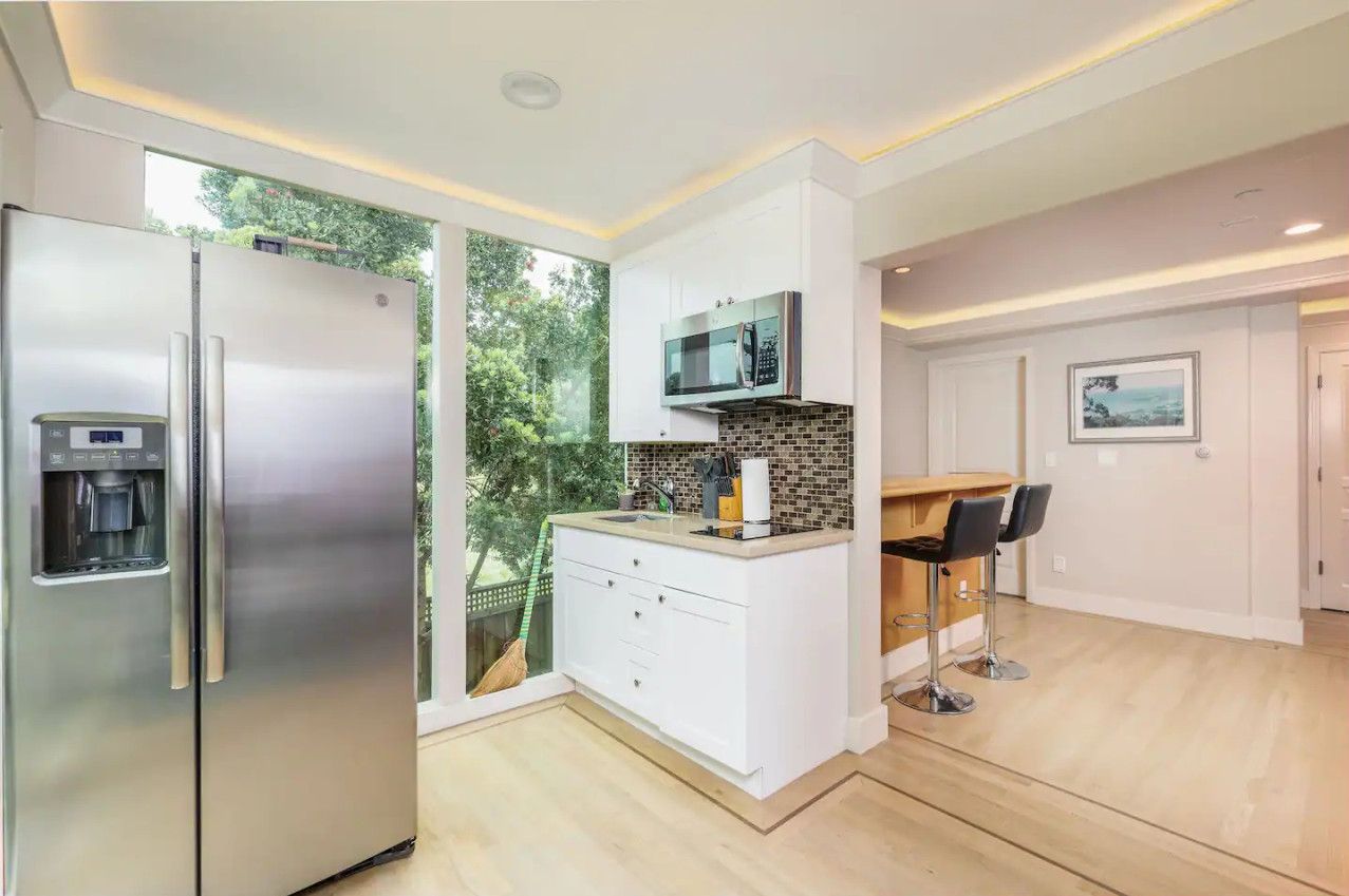 A modern kitchen with a stainless steel refrigerator, a microwave, and a built-in coffee machine.