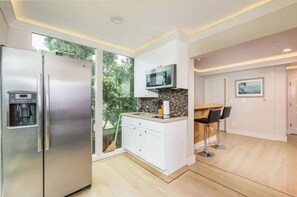 Una cucina moderna con un frigorifero in acciaio inossidabile, un forno a microonde e una macchina per il caffè integrata.