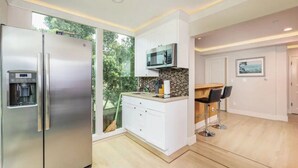 A modern kitchen with a stainless steel refrigerator, a microwave, and a built-in coffee machine. - Seaside Escape: 1 block to Beach, Private Hot Tub, Fire Pit & BBQ (El Granada)
