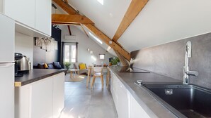 A modern kitchen with a large island, a built-in sink, and wooden beams on the ceiling.