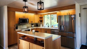 A modern kitchen with wooden cabinets, stainless steel appliances, and pendant lighting. - Crescent Beach Retreat: Cozy 4br House (Port Angeles)