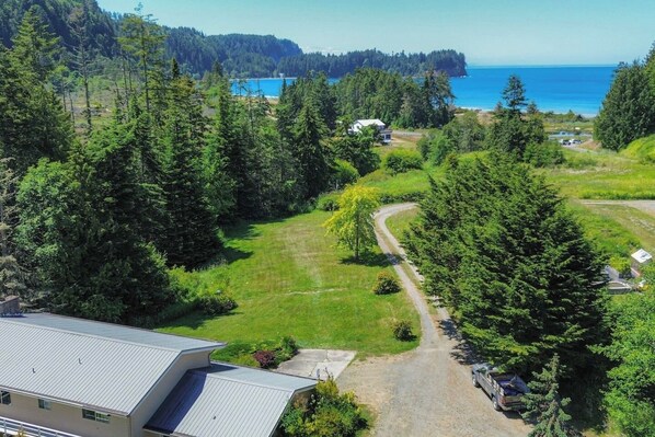 A residential area with a clear view of a coastal landscape, including a road leading to houses and a body of water.