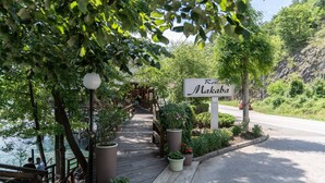 Señalización de 'Resort Makaba' con un paseo de madera que conduce a un edificio, rodeado de follaje y una masa de agua.