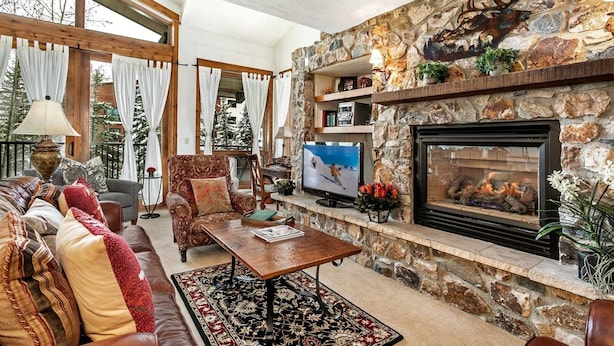A cozy living room with a stone fireplace, a television, and comfortable seating. - Antlers Condominiums - Vail (Vail)