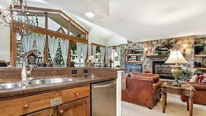 A kitchen with granite countertops, a stainless steel sink, wooden cabinets, and a dishwasher. - Antlers Condominiums - Vail (Vail)
