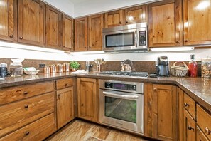 A kitchen with wooden cabinets, stainless steel appliances, and a granite countertop. - Antlers Condominiums - Vail (Vail)