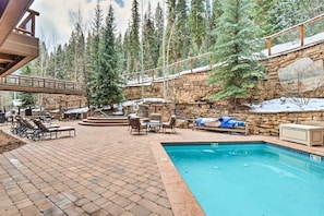 A pool area with lounge chairs and a stone wall. - The Timbers Ski In Ski Out at River Run (Keystone)