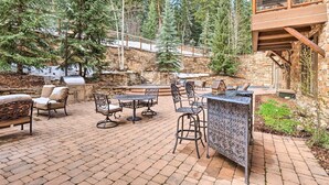 An outdoor patio with stone flooring, a barbecue grill, and outdoor furniture. - The Timbers Ski In Ski Out at River Run (Keystone)