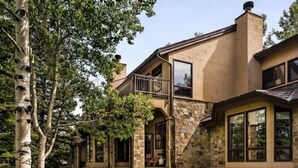 A two-story house with a stone facade, large windows, and a balcony. - Snowmass Woodrun V Residences (Snowmass Village)