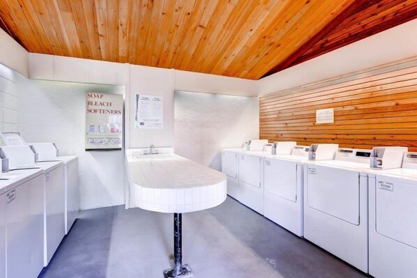 A modern bathroom with a wooden ceiling, white fixtures, and a sign about soap and bleach softeners. - Evergreen Condominiums, Keystone (Keystone)