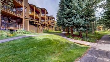 A multi-story building with balconies and a well-maintained lawn.