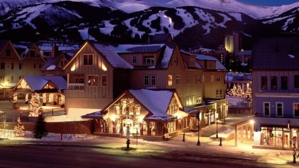 A snow-covered mountain town at night with illuminated buildings and a prominent hotel with a snow-covered roof. - Breckenridge Main Street Condominiums (Breckenridge)