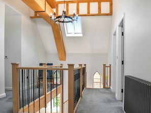 Una escalera con barandas de madera y un candelabro, que conduce a una zona superior con tragaluces.