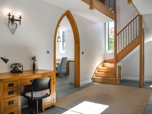 Una habitación amplia con un escritorio de madera, una silla, una escalera y vistas al exterior.