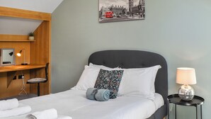 A neatly made bed with white linens, a dark headboard, and a single decorative pillow.