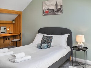 A neatly made bed with white linens, a dark headboard, and a single decorative pillow.