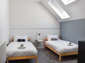 A room with two single beds, a small table, a lamp, a radiator, and a skylight. - 5 bedroom accommodation in Ramsgate (Ramsgate)