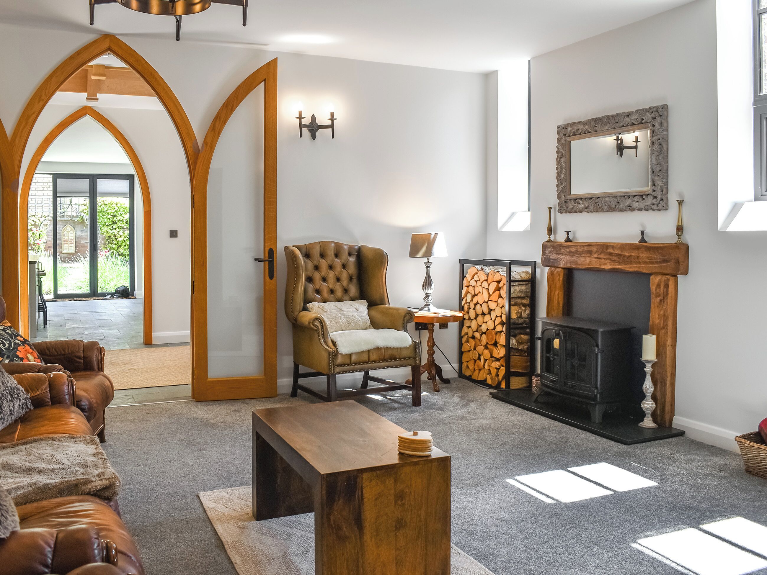 Un salon doté d’une cheminée, d’un canapé en cuir, d’une table basse en bois et d’une porte donnant sur un balcon.