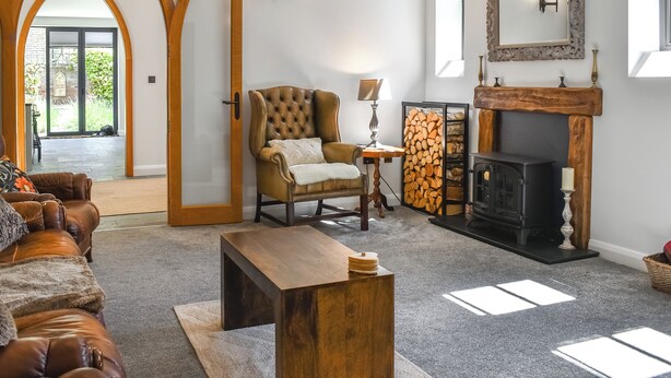 A living room with a fireplace, a leather sofa, a wooden coffee table, and a door leading to a balcony.