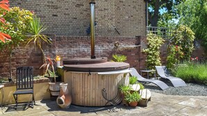A patio with a hot tub, seating, and potted plants.