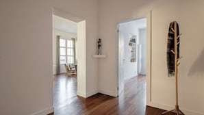A hallway with wooden flooring, a coat rack, and a shelf with a statue. - Casa Madà vicino al Politeama by Wonderful Italy (Palermo)