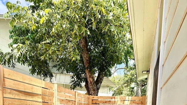A patio with a wooden fence, a table and chairs, and potted plants. - Stylish Heaven/Central SA (San Antonio)