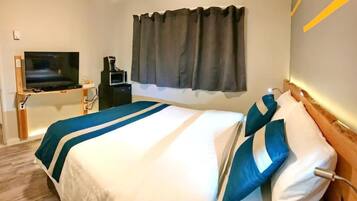 A hotel room with a bed, a TV on a stand, a coffee machine, and a window with curtains.