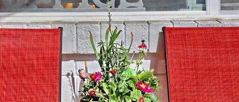 A small table with a potted plant in front of a window with the word "OFFICE" on it.