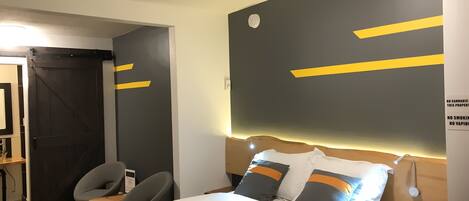 Ein Hotelzimmer mit Bett, Nachttischen, Schreibtisch und Stuhl. Ein Schild an der Wand weist darauf hin, dass Cannabis, Rauchen und Dampfen verboten sind.