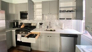 Una cocina moderna con armarios grises, una estufa de acero inoxidable, un lavavajillas y un microondas.