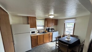 A compact kitchen with wooden cabinets, a refrigerator, a microwave, a sink, and a dining table with chairs. - Stay at this Port Clinton guest unit w/boat/trailer parking & plug in, AC, WiFi! (Port Clinton)