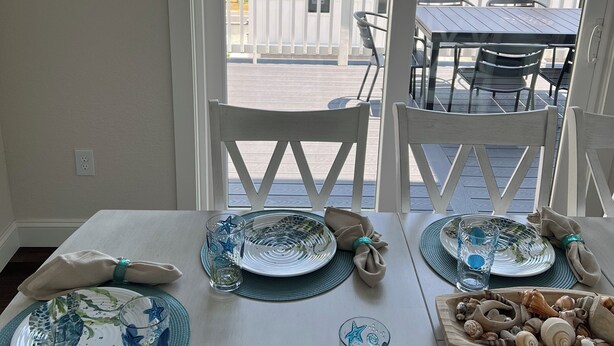 Een eethoek met een tafel voor twee personen, uitgevoerd in een kustthema met zeesterren en schelpen.