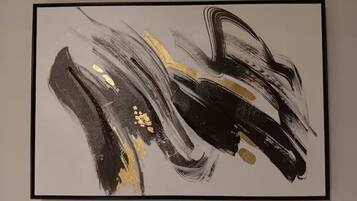 A framed abstract painting with black, white, and gold brush strokes.