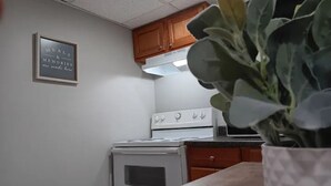 Een keuken met een witte kookplaat, houten kastjes en een plant in een pot op het aanrecht.