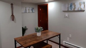 Een kamer met een houten tafel, een potplant, een deur en abstracte kunst aan de muur.
