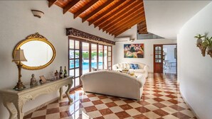 Una habitación amplia con suelo de cuadros, un sofá blanco, un espejo grande y un cuadro en la pared.