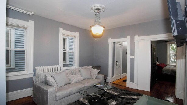 A living room with a grey sofa, a glass coffee table, and a patterned rug. - Remodeled, Spacious, Furnished - Brady St Apartment for Monthly Rental (Milwaukee)