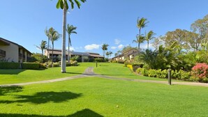 A well-maintained lawn with a pathway leading to a building with a modern design. - Relaxed Island Living with Ocean & Golf Views (Waikoloa Village)