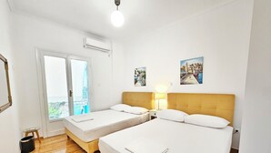 Une chambre d’hôtel avec deux lits, un plancher en bois, un balcon avec vue et un ventilateur de plafond.