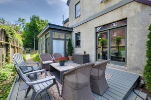 Une terrasse extérieure aménagée avec des meubles en osier, une table et des plantes en pot.