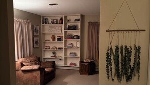 A cozy living room with a brown leather sofa, a bookshelf filled with books and decorative items, and a sign that reads "FARMHOUSE".