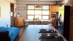 A kitchen with a central island, wooden cabinets, a refrigerator, and a dining area with a table and chairs.