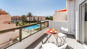 A balcony with a table, chairs, and a view of a swimming pool and buildings. - CT 288 AL   Faro's Retamar Cuddly Nest for 2 (Almería)